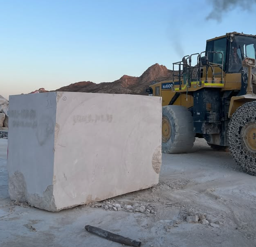 Cream marble block beside a quarry loader